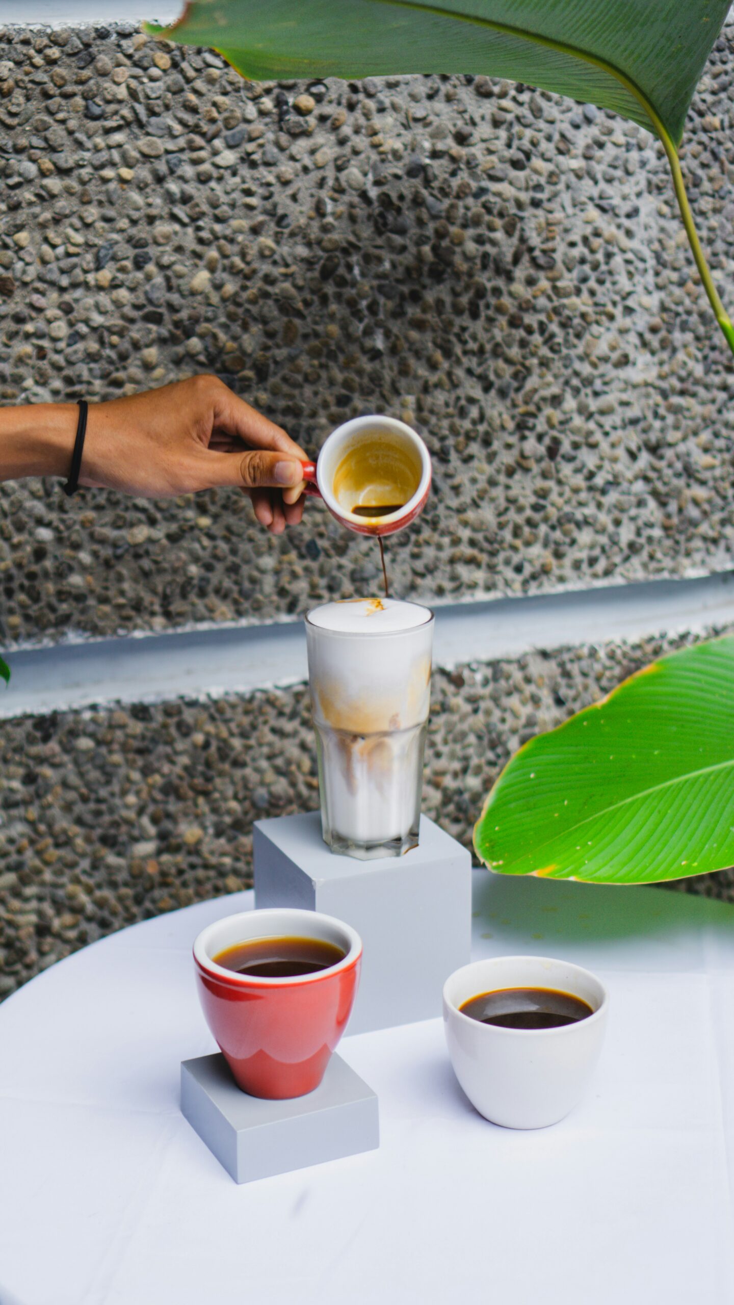 a hand pouring an espresso in milk